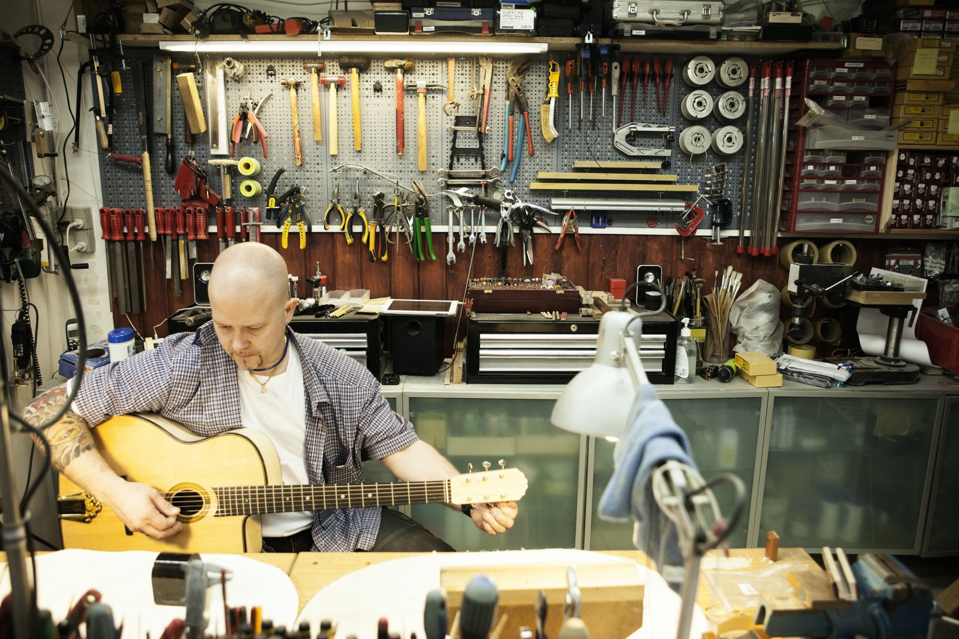 Guitar maker tuning acoustic guitar in workshop